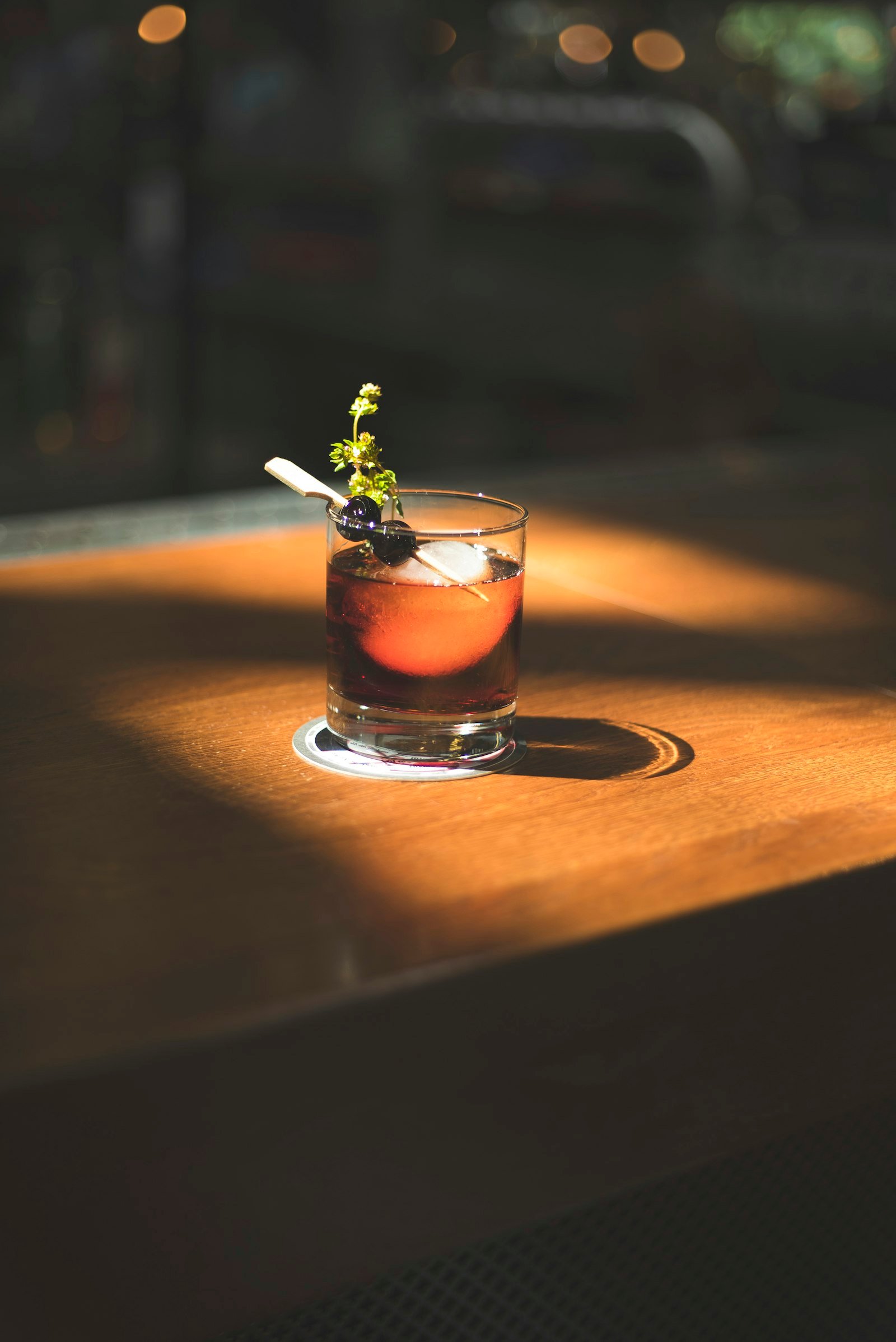 A cocktail with olives and herbs in a rocks glass