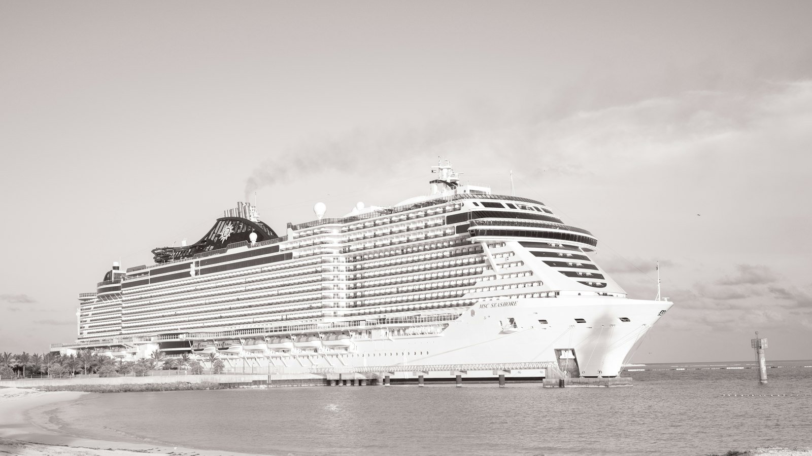 A large cruise ship docked beside a beach